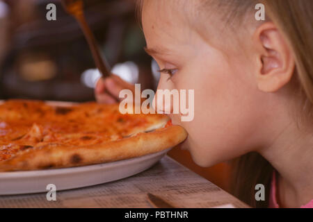 Cute little girl eating pizza savoureuse et délicieuse. Banque D'Images