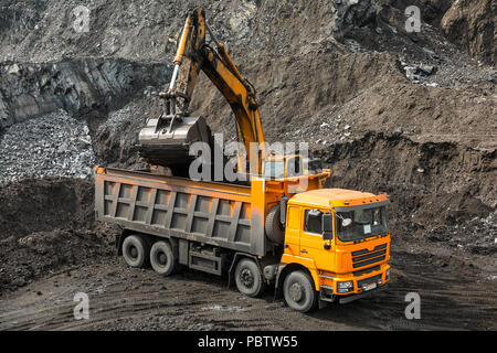 Grande carrière dump truck. Le chargement de la benne dans la roche. Chargement de charbon dans le corps chariot. Les minéraux utiles de production. Mining truck les engins d'extraction, de transport du charbon à ciel ouvert de la la production de charbon. Banque D'Images
