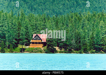 Maison en bois près du lac bleu dans la forêt dense parmi les arbres. Dans la base touristique de la taïga sibérienne. Maison à ossature en bois. Altaï. La Russie Banque D'Images