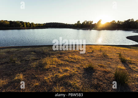 Bien au-dessus des arbres et leurs rayons se reflétant dans les eaux du lac et d'éclairage les herbes de la colline, Espagne Banque D'Images