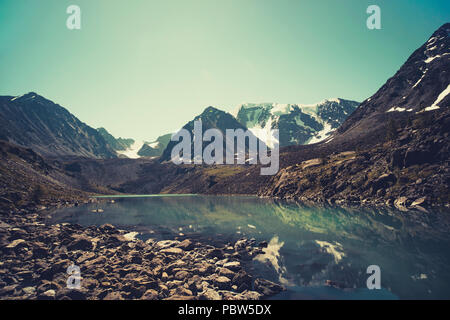 Dans le lac avec les montagnes des Alpes, tonique en arrière plan photo. Paysage de matin d'été. Reflet de montagnes aux sommets enneigés dans crystal clear w Banque D'Images