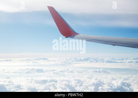 Vue aérienne de la fenêtre de l'avion sur les nuages et une aile d'avion dans le ciel bleu. Voler et voyager concept. Banque D'Images