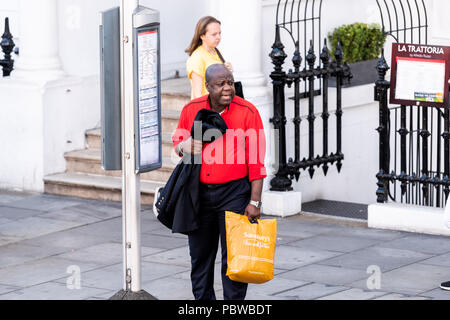 Londres, Royaume-Uni - 22 juin 2018 Quartier : quartier de Kensington sud homme portant des sacs d'épicerie Sainsbury's en attente de cross street, arrêt de bus Banque D'Images