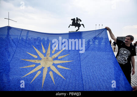 Thessalonique, Grèce. 30 juillet, 2018. Les gens tiennent un drapeau avec le Soleil de Vergina en face de la statue d'Alexandre le Grand sur le front de mer de Thessalonique. Des centaines de personnes ont dansé au bord de l'eau de la partie nord de Thessalonique, un Grec Macédonien traditionnel danse appelée ''Mmacédonienne Syrto'', afin de protester contre l'Accord sur Prespa débat entre la Grèce et la Macédoine. Credit : Giannis Papanikos/ZUMA/Alamy Fil Live News Banque D'Images