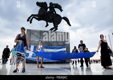 Thessalonique, Grèce. 30 juillet, 2018. Les gens tiennent un drapeau avec le Soleil de Vergina en face d'Alexandre le Grand statue sur le front de mer de Thessalonique. Des centaines de personnes ont dansé au bord de l'eau de la partie nord de Thessalonique, un Grec Macédonien traditionnel danse appelée ''Mmacédonienne Syrto'', afin de protester contre l'Accord sur Prespa débat entre la Grèce et la Macédoine. Credit : Giannis Papanikos/ZUMA/Alamy Fil Live News Banque D'Images