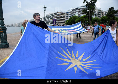 Thessalonique, Grèce. 30 juillet, 2018. Les gens tiennent un drapeau avec le Soleil de Vergina comme ils marchent sur le front de mer de Thessalonique. Des centaines de personnes ont dansé au bord de l'eau de la partie nord de Thessalonique, un Grec Macédonien traditionnel danse appelée ''Mmacédonienne Syrto'', afin de protester contre l'Accord sur Prespa débat entre la Grèce et la Macédoine. Credit : Giannis Papanikos/ZUMA/Alamy Fil Live News Banque D'Images