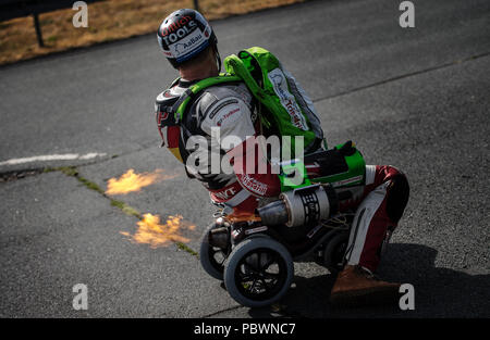 29 juillet 2018, Darmstadt Allemagne : une puissante explosion de feu sort de l'injecteur, comme les moteurs en marche. Dirk Auer, plasturgie ingénieur de Gross-Gerau, veut accélérer de 0 à 100 km/h en 2,3 secondes avec un jet-powered by Bobby car. Le renforcement de l'aire de véhicule est équipé d'un moteur, et Auer possède deux réacteurs supplémentaires sur ses avant-bras. L'athlète extrême tentera d'établir un record du monde à l'aéroport de Bottrop-Kirchhellen le 5 août 2018. Photo : Andreas Arnold/dpa Banque D'Images