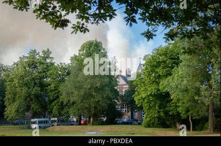 La fumée des incendies landes sur la colline d'hiver et de l'Ouest Pennine Moors ciel bleu se cache derrière les maisons et Rivington & Blackrod Grammar School, Juin 2018 Banque D'Images