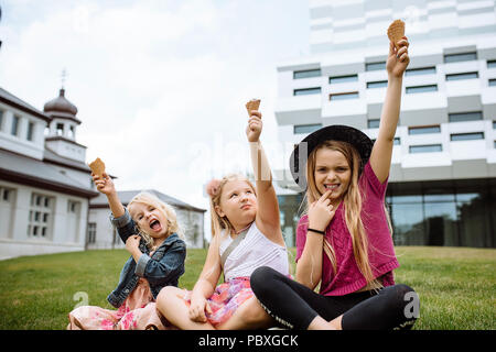 Happy smiling kids eating ice cream en plein air dans le parc d'été. Trois sœurs Banque D'Images