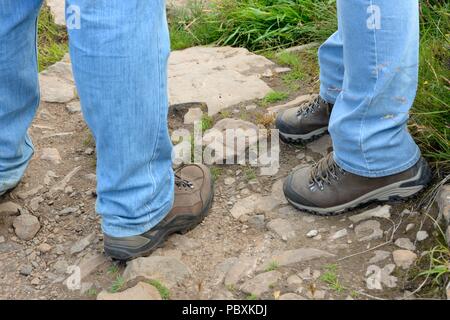 Un homme et une femme portant des chaussures de randonnée sur un sentier rocheux bien usé. Banque D'Images