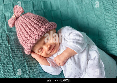 Smiling nouveau-né bébé dort profondément. Close up portrait of smiling baby girl joyeusement sur des vêtements de laine verte. Banque D'Images