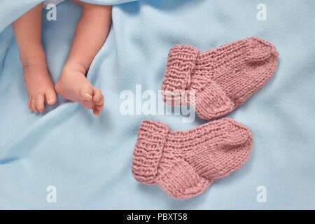 Tout petit bébé nouveau-né pieds et chaussettes de laine chaude. Paire de chaussettes tricotées. Couverture bleue. Banque D'Images