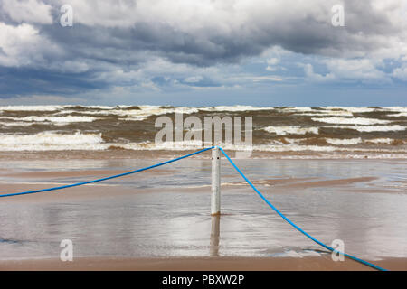 Corde bleu sur un poteau, sur une plage de sable blanc de la mer Baltique dans les nuages de tempête sur la mer Banque D'Images