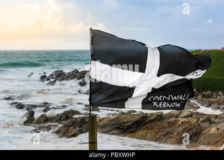 Un drapeau St Piran voltigeant dans le vent sur la côte à dans Fistral Newquay Cornwall. Banque D'Images