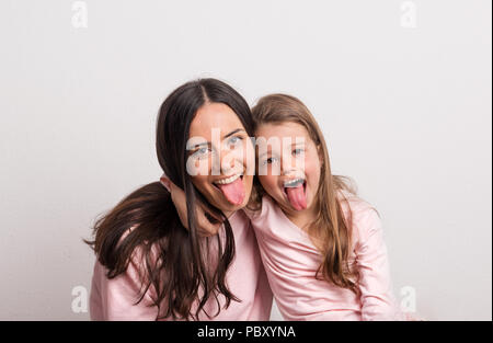 Une petite fille et sa mère coller langues dans un studio. Banque D'Images