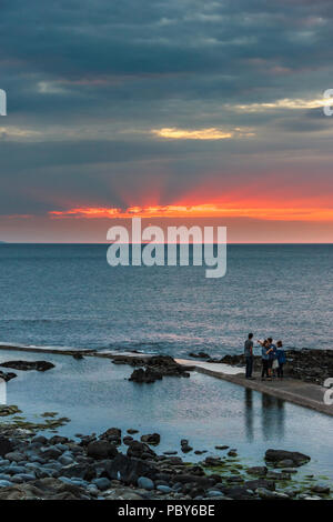 Un groupe de deux hommes et deux femmes regardant le coucher du soleil à Westward Ho !, Devon, UK, silhouetté contre le ciel Banque D'Images
