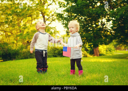 Heureux adorable petit blond Caucasian girl and boy smiling rire tenant la main et en agitant le drapeau américain à l'extérieur de célébrer le 4 juillet, Independenc Banque D'Images