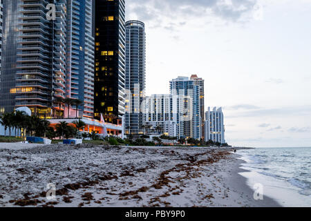 Sunny Isles Beach, appartement, condo, bâtiments de l'hôtel pendant le coucher du soleil sombre soir heure bleue nuit à Miami, Floride avec sable gratte-ciel, les vagues sur le rivage Banque D'Images