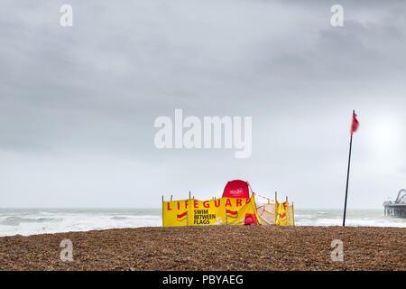 Vue d'une base de sauveteur sur la plage de Brighton. Le drapeau rouge est battant et avise les personnes de nager entre les drapeaux mais c'est trop accidenté pour nager dans la mer. Banque D'Images