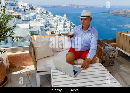 Homme dans un café au bord de la mer travaille sur un ordinateur portable Banque D'Images