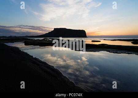 Reflet de nuages dans océan au lever du soleil à Ilchulbong cratère du volcan avec vue sur océan et vert mousse, pierres, Seongsan l'île de Jeju, Corée du Sud Banque D'Images