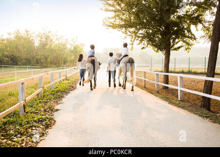 Cheerful young Chinese family riding horses Banque D'Images