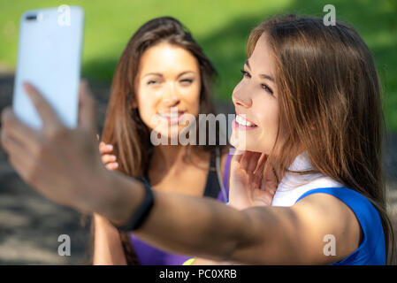 Mode de vie de la génération Y - deux filles sportives prenant un sourire et selfies après l'extérieur de la formation sur une journée ensoleillée. Banque D'Images