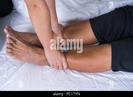 Close up hands massage femme de faire de la douleur aux jambes dans un lit Banque D'Images