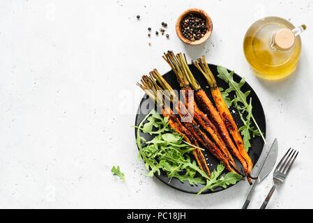 Carottes rôties et salade végétarienne vert frais. Vue d'en haut. Salade végétalienne saine sur la plaque noire Banque D'Images