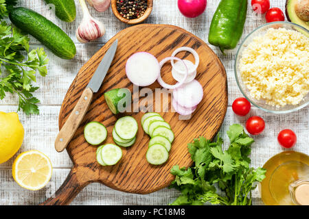 Arrière-plan de cuisson. Légumes frais sur planche à découper en bois. Concombre, purple oignon, persil, citron, radis et tomates. Préparation de la Salade Banque D'Images