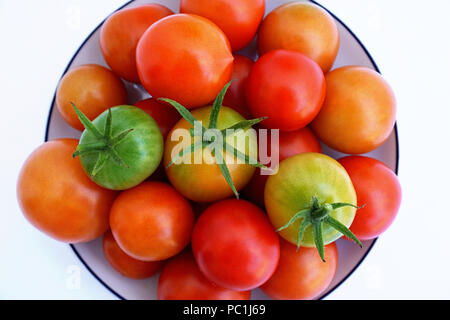 Les frais vert et rouge, mûr et tomates cerises non mûres sur une soucoupe blanche, vue du dessus. Les légumes bio se développent sur le jardin d'accueil Banque D'Images