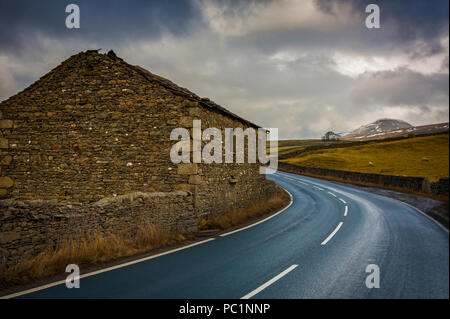 Une grange sur un virage sur une route sinueuse menant vers Pen-Y-Ghent vu dans la distance. Banque D'Images