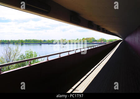 La perspective de lis dans un tunnel sous le pont sur la rivière avec un bateau et arbres au printemps Banque D'Images