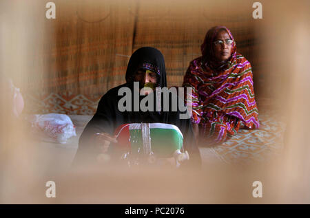 Une femme portant un tricot métallique burqa drapeau Emirati dans l'heritage village à Fujairah. Le village est place aux éléments montrant Emirati la culture. Banque D'Images