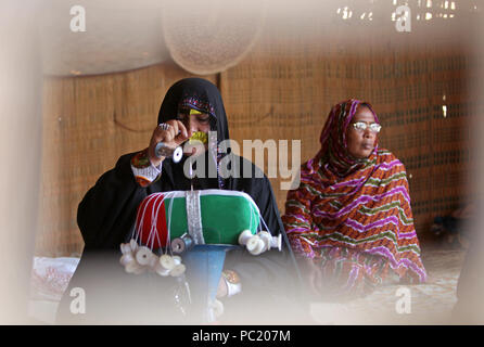 Une femme portant un tricot métallique burqa drapeau Emirati dans l'heritage village à Fujairah. Le village est place aux éléments montrant Emirati la culture. Banque D'Images