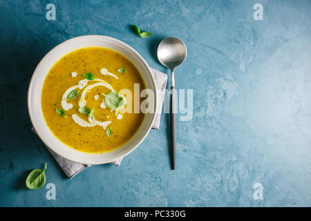 Soupe d'automne appétissant savoureux à la citrouille et à la crème fraîche dans un bol servi sur table. Vue rapprochée d'en haut Banque D'Images