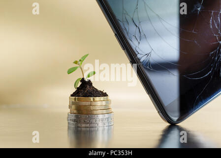 Téléphone cassé et affichage des pièces d'argent et d'or dans le sol avec jeune plant. Concept d'entreprise de réparation de téléphones portables Banque D'Images