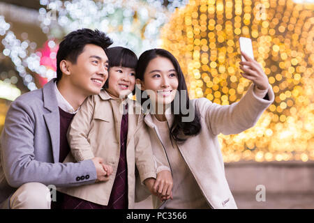 Cheerful young Chinese family taking self portrait with smart phone Banque D'Images