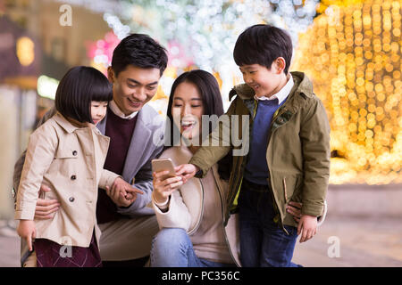 Cheerful young famille chinoise à l'aide de smart phone Banque D'Images