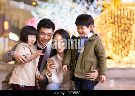 Cheerful young famille chinoise à l'aide de smart phone Banque D'Images