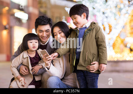 Cheerful young famille chinoise à l'aide de smart phone Banque D'Images