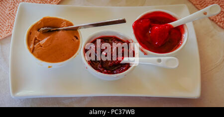 Plateau avec des condiments et des écarts pour le petit-déjeuner bagels ou toast : beurre d'arachide, confiture de petits fruits, confiture de cerises Banque D'Images