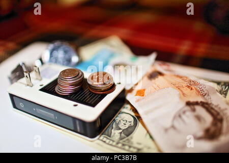 Temps, énergie, argent concept photo avec batterie rechargeable, montre bracelet, dollars et livre sterling billets et quelques pièces foiré dans le cadre Banque D'Images