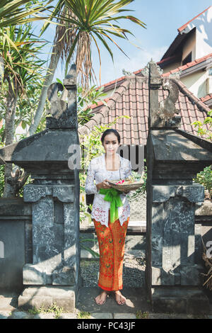 Femme portant des vêtements traditionnels balinais apportant canang sari Banque D'Images