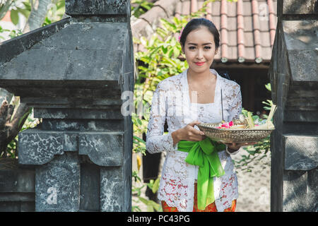 Femme portant des vêtements traditionnels balinais apportant canang sari Banque D'Images