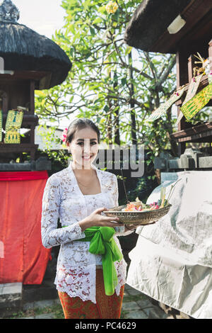 Femme portant des vêtements traditionnels balinais apportant canang sari Banque D'Images