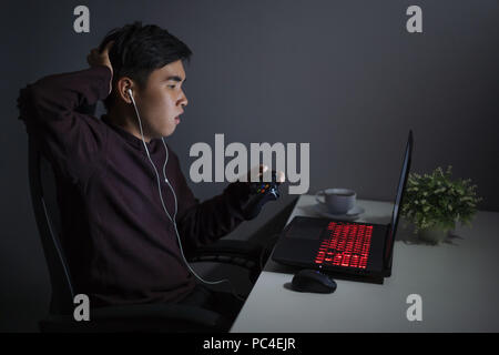 Jeune homme déprimé a souligné à l'aide de joystick pour jouer à des jeux Banque D'Images