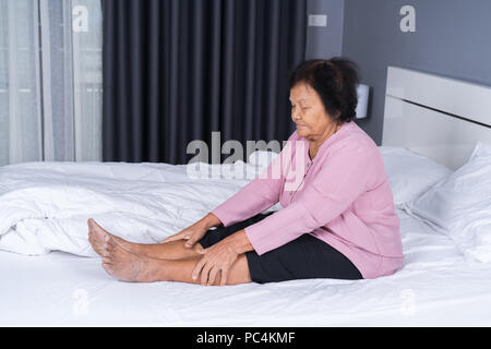 Senior woman avec la douleur de jambe dans un lit Banque D'Images