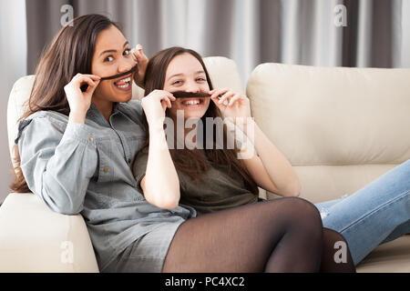 Deux soeurs jouant avec moustache cheveux. Silly funny moment ensemble Banque D'Images