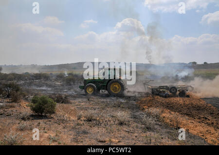 Agriculteur laboure un champ de gravure pour contenir le feu. Cet incendie a été causé par des bombes qui ont été palestiniens Kite par avion en provenance de Gaza avec une essence allumé imbibé Banque D'Images